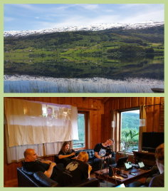 2 pictures from the cabin. First picture shows a mirror-still lake with snow covered, yet green mountains in the background. Second picture is from inside the cabin with participants talking together.